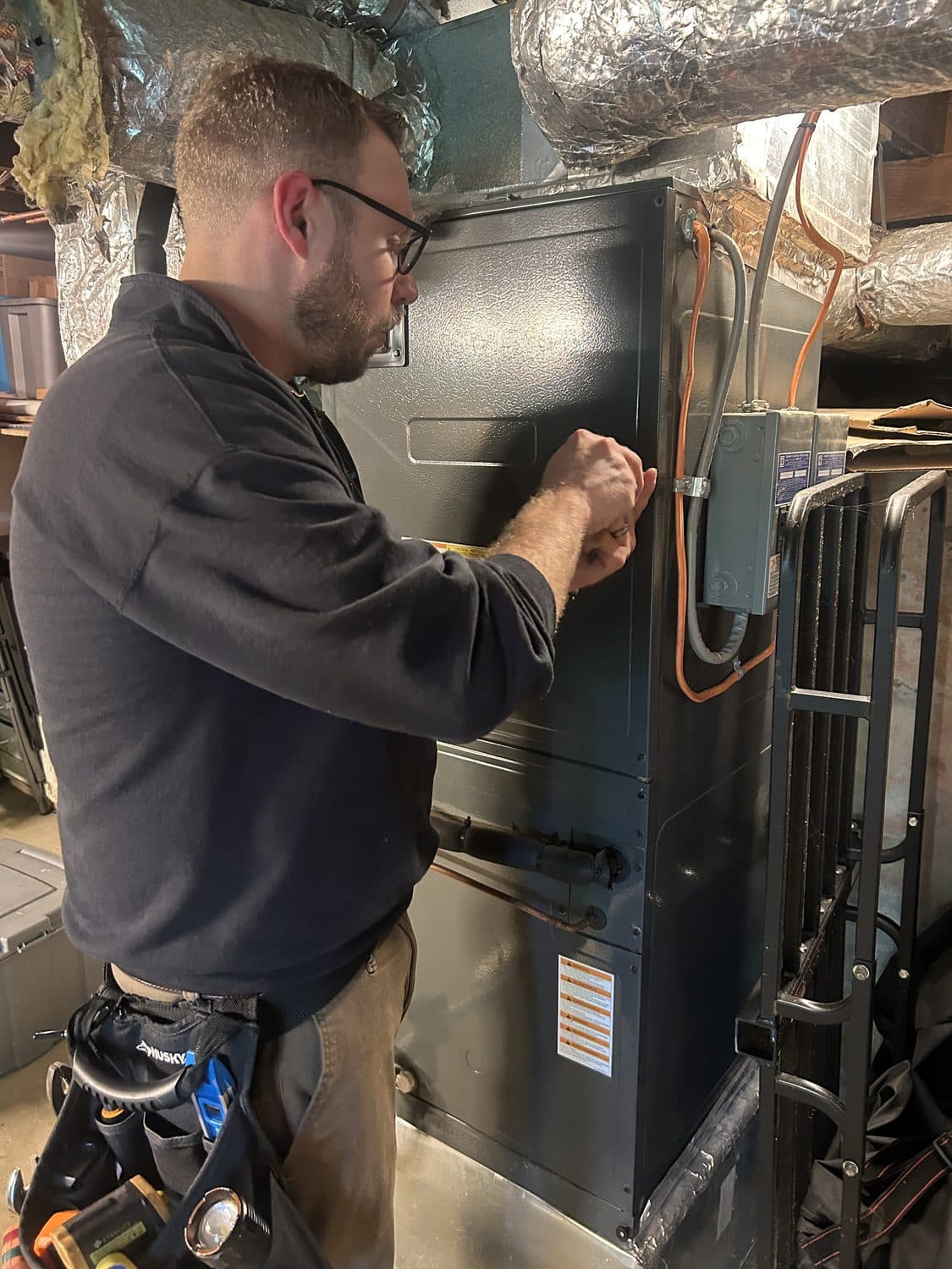 Matt inspecting an HVAC furnace system in a basement